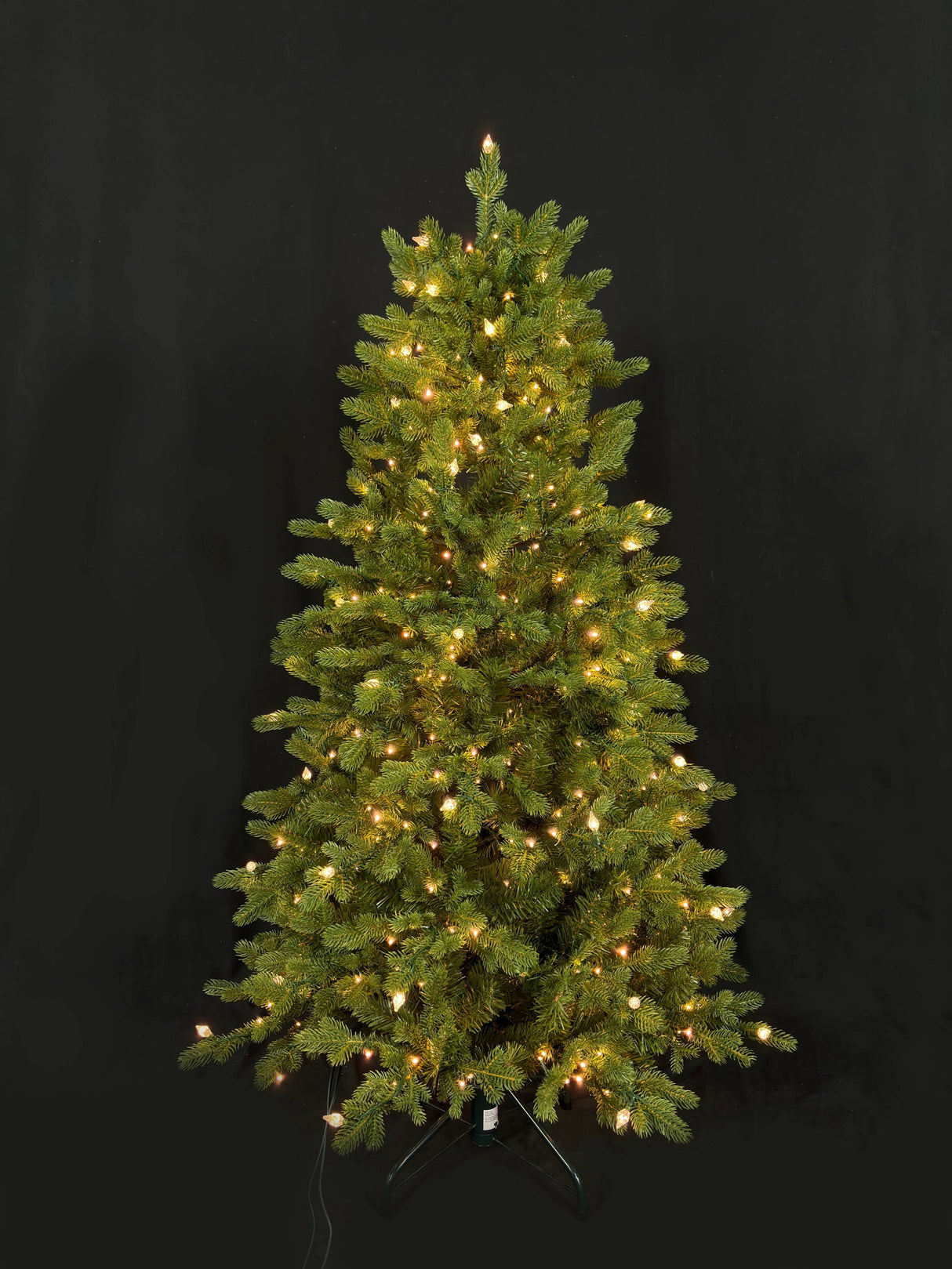 This image shows this specific artificial tree pre-lit with Warm White Starry Lights. This tree is up against a black background.
