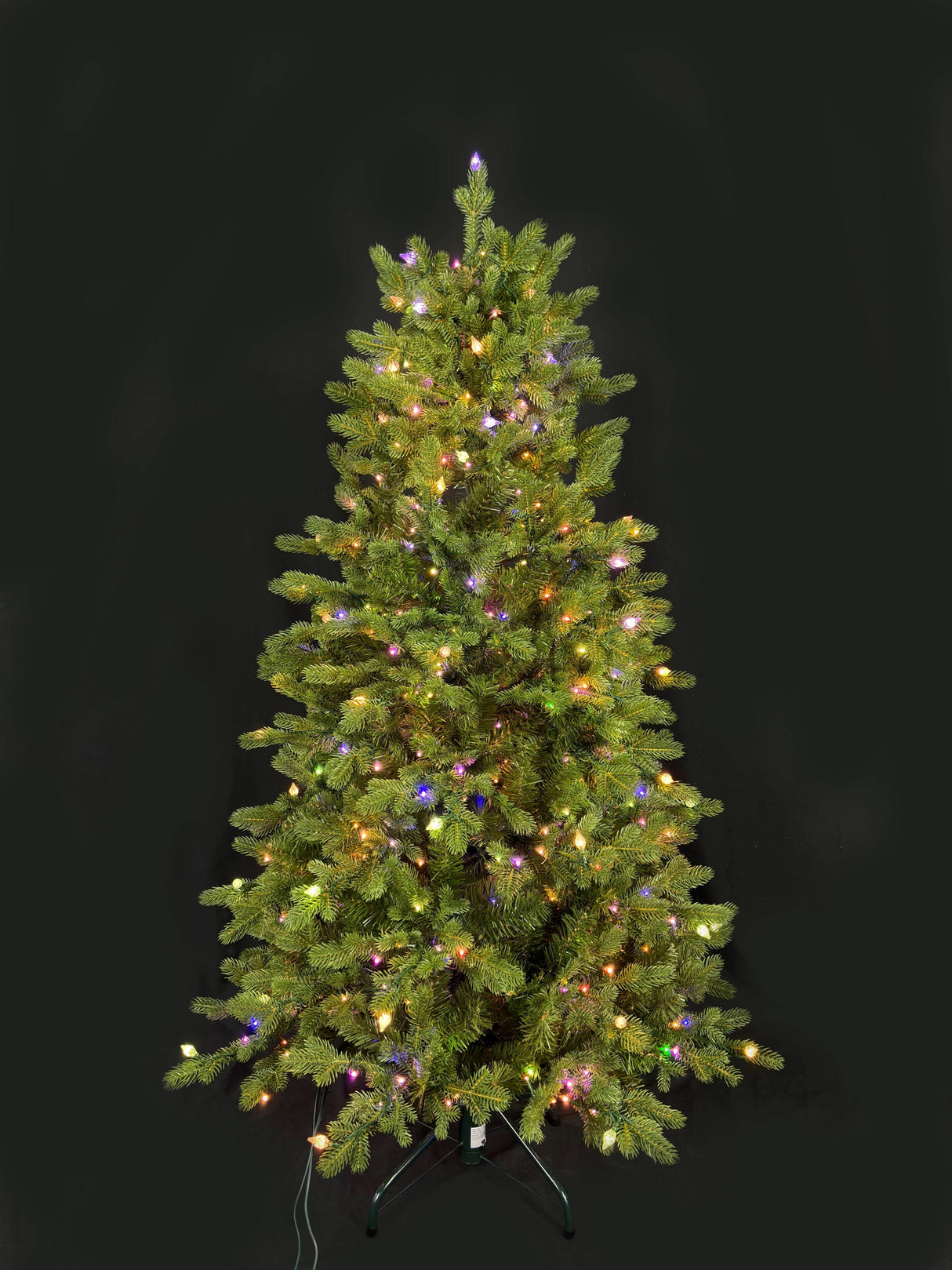 This image shows this specific artificial tree pre-lit with Multi-Colored Starry Lights. This tree is up against a black background.