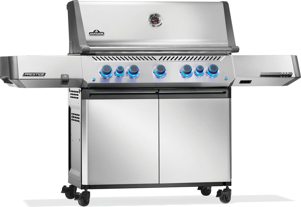 Silver and gray Napoleon grill. There is a built-in thermometer on the lid, there are two shelves outstretched, seven buttons and a cabinet that opens up underneath. This is the left side view.