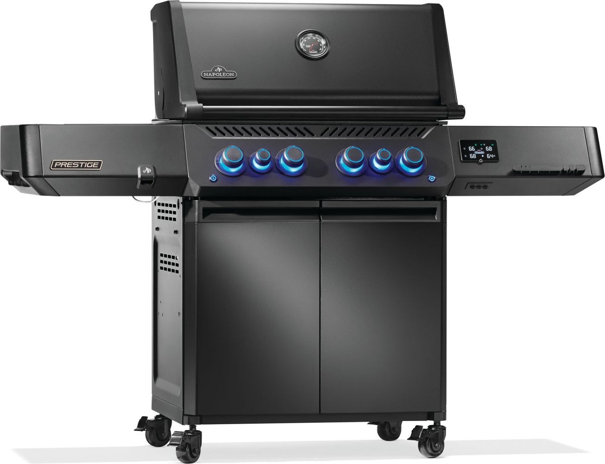 Black Napoleon grill. There is a built-in thermometer on the lid, there are two shelves outstretched, six buttons and a cabinet that opens up underneath. This is the left side view.