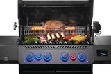 This is an up close view of food cooking on the grill. There's meat cooking on the rotisserie feature. There's broccoli, onions, tomatoes and corn on the cob cooking on the grates.