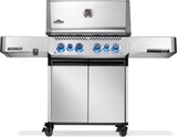 Silver and gray Napoleon grill. There is a built-in thermometer on the lid, there are two shelves outstretched, six buttons and a cabinet that opens up underneath. This is the front view.