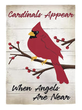 A flag that looks like it's made of faded wood. It reads "Cardinals appear when angels are near" in cursive. It features a cardinal standing on a branch with red berries on it.