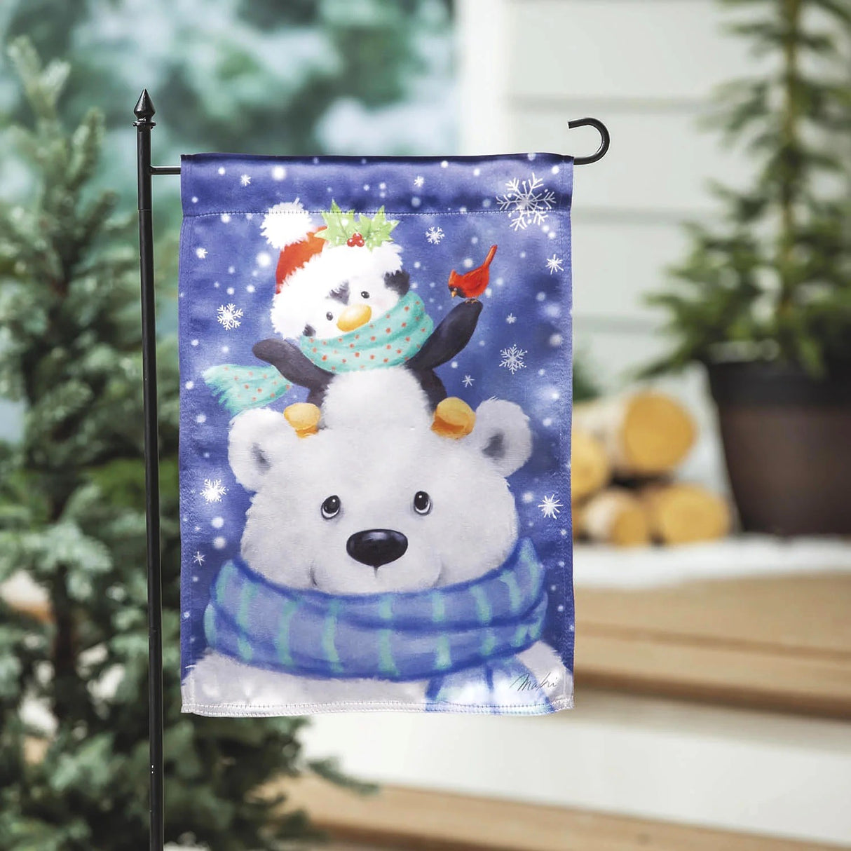 Blue flag that features a cute polar bear wearing a blue and green striped scarf. There's a cute penguin sitting on the polar bear's head. The penguin is wearing a Santa hat and a teal scarf with pink polka dots. There's a cardinal sitting on the penguin's flipper.