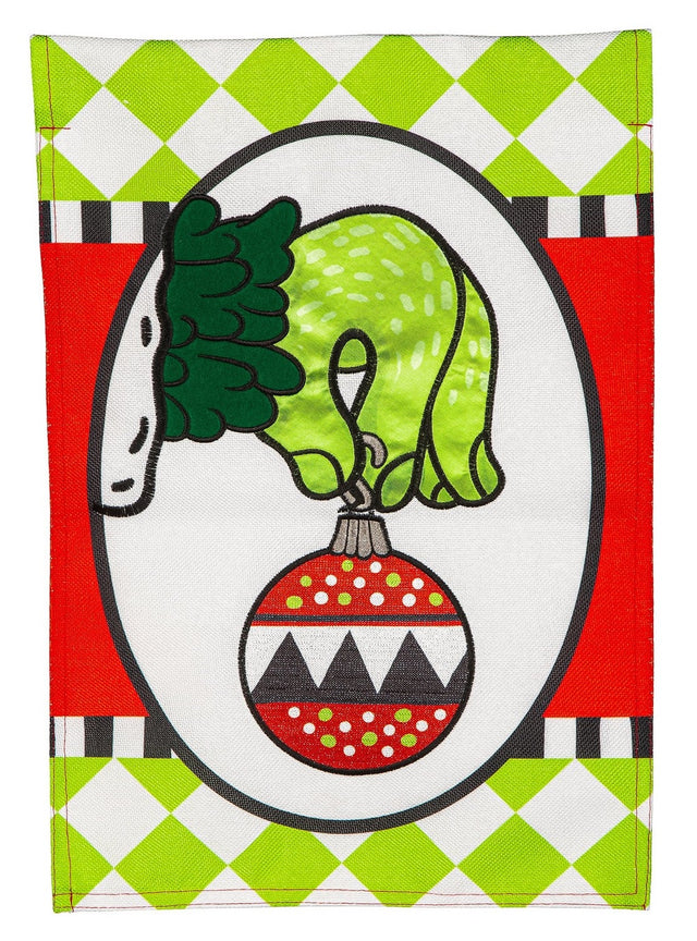 Flag with a cartoon depiction of The Grinch's green hand holding an ornament. There are also lime green diamonds, a black and white stripe and red designs.