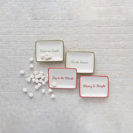 Decorative stoneware dish. One dish reads "Tis the Season" and has a green border. One dish reads "Merry & Bright" and has a red border. One dish reads "Peace on Earth" and has a green border. One dish reads "Joy to the World" and has a red border. This image shows some candy in the dishes.