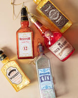 Ornament shaped like a miniature bottle of alcohol. One ornament is red and reads "Aged Brandy." One ornament is yellow and reads "Whiskey." One ornament is orange and reads "Scotch." One ornament is yellow and reads "Bourbon." One ornament is light blue and reads "Gin." Each ornament has glitter inside.