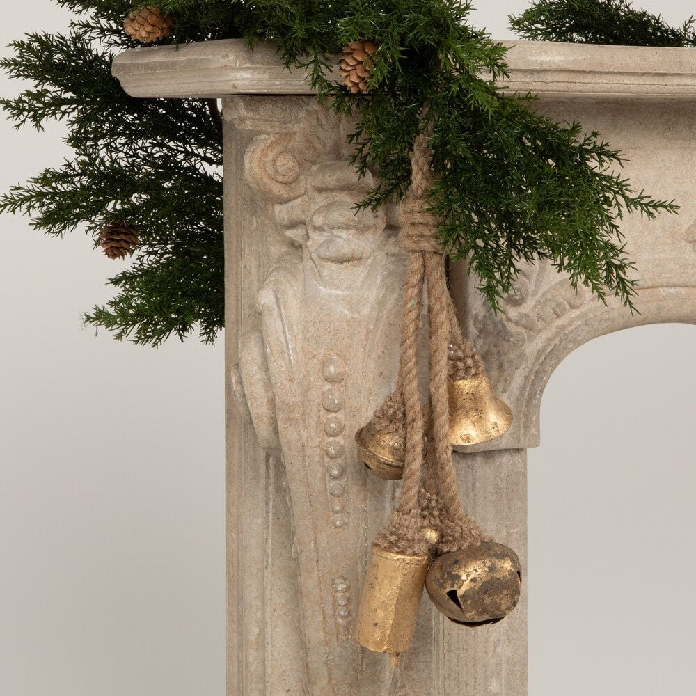 This is a lifestyle image showing the bells hanging from a garland that's draped over a fireplace.