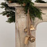 This is a lifestyle image showing the bells hanging from a garland that's draped over a fireplace.
