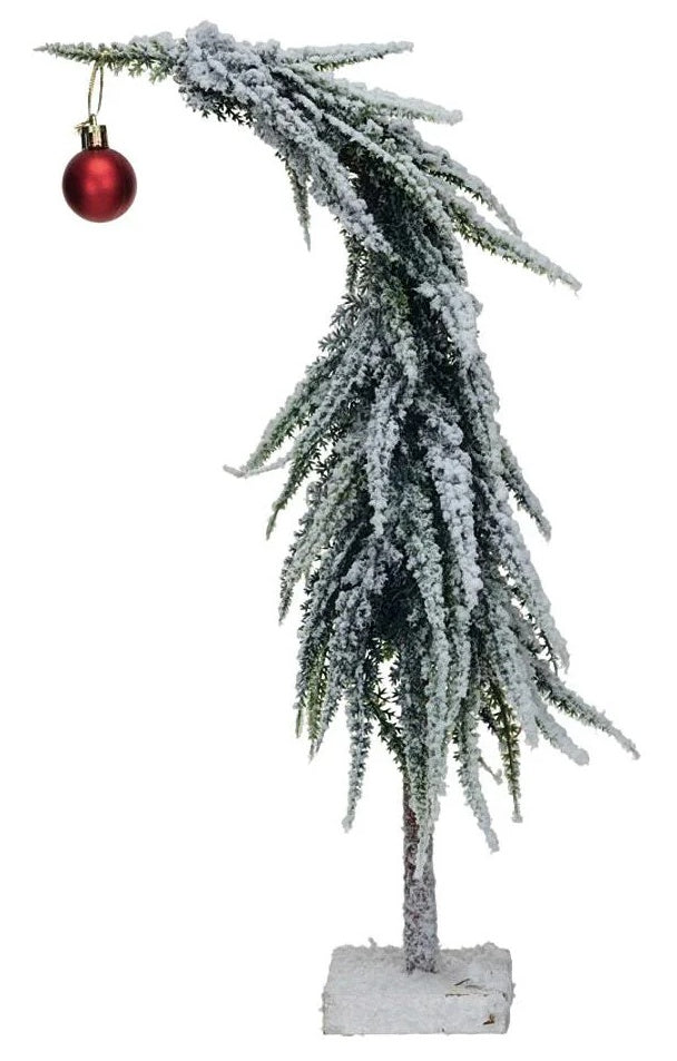 This image shows a small drooping tree covered in fake snow with a flat, wooden base. There's a shiny, red ornament hanging from the top causing the tree to "droop."