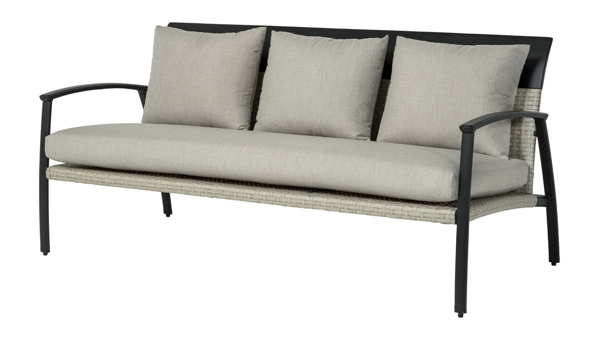 A sofa made up of aluminum and wicker with tan cushions