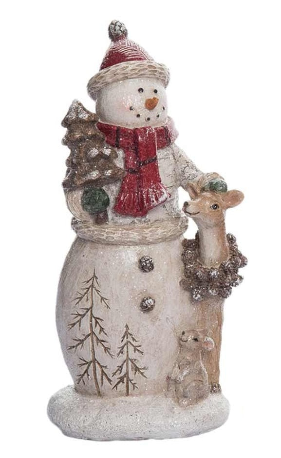 This snowman is wearing a red winter hat, a red and black scarf and is holding a small tree. There are two bare trees etched into the base of the snowman while a smiling deer and a smiling squirrel stand nearby.