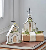 Ornament shaped like a church. One church features a wreath near the steeple. One church features a garland near the steeple.