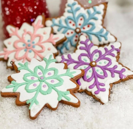 Ornament designed to look like a frosted gingerbread cookie. Two are shaped like six-point stars and two are shaped like snowflakes. They're all decorated with intricate designs. You get one, this image shows all four options.