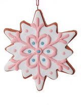 Ornament designed to look like a frosted gingerbread cookie. Two are shaped like six-point stars and two are shaped like snowflakes. They're all decorated with intricate designs. You get one, this image shows all four options.