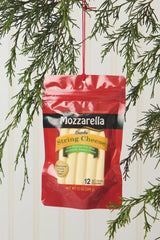 An ornament shaped like a package filled with string cheese. It reads "Mozzarella. String cheese snacks. Low moisture part-skim mozzarella natural cheese. A natural source of calcium with 7 g of Protein. 12 90 calorie snacks."