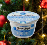 Ornament shaped like a cup of yogurt. One ornament is white and red and "flavored" strawberry. One ornament is white and blue and "flavored" blueberry. One ornament is white and orange and "flavored" peach. One ornament is white and blue and "flavored" Greek-style.