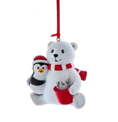 This ornament features a polar bear and a penguin smiling over a red bucket of fish. Hangs from a red ribbon.