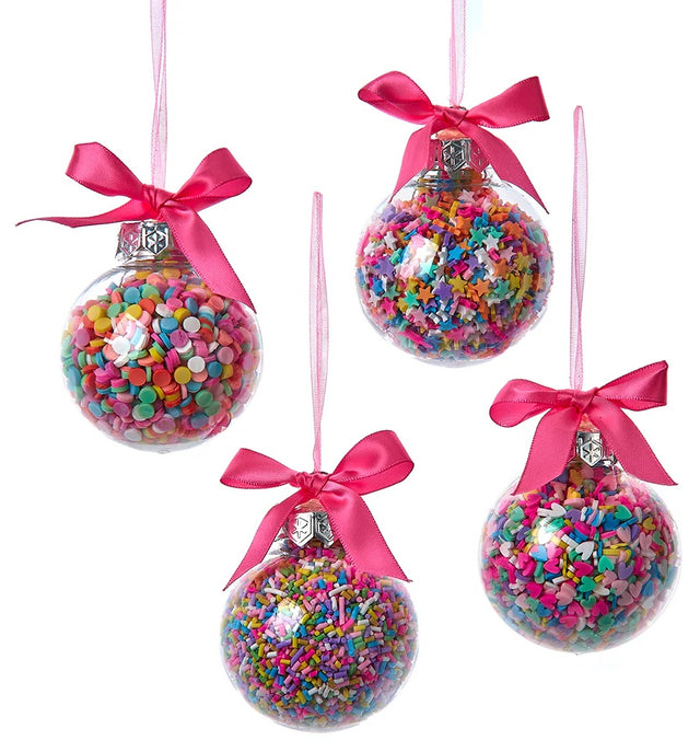 Glass bauble ornament with multi-colored sprinkles inside. One ornament features round sprinkles.
One ornament features star sprinkles. One ornament features tube sprinkles. One ornament features heart sprinkles. Each ornament is tied with a hot pink bow.