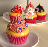 Christmas ornaments shaped like cupcakes with different colored frosting and candies on them.