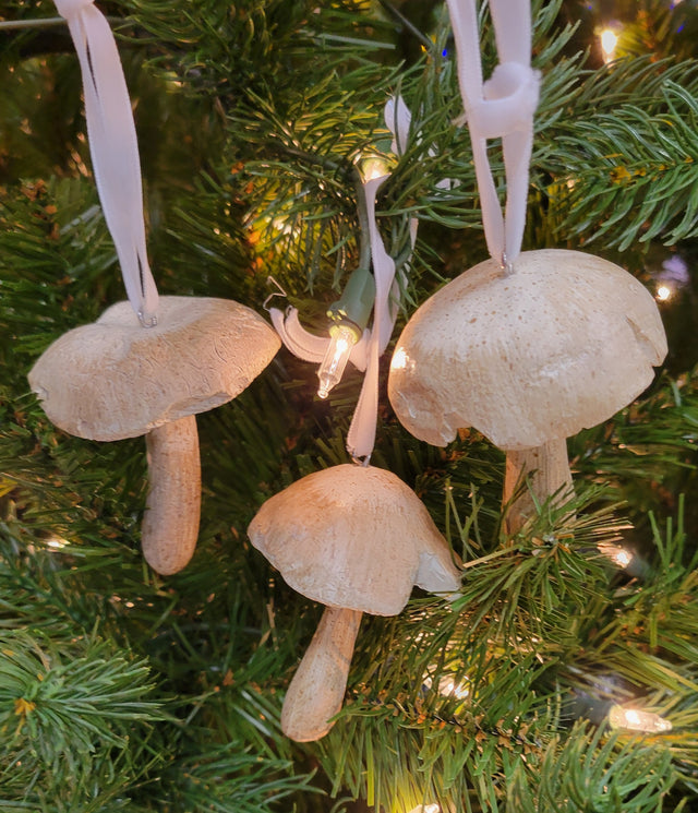 This is a lifestyle image showing the three different mushroom ornaments hanging on a tree.