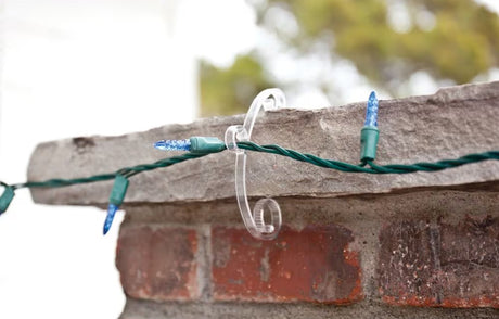 This is a lifestyle image showing the clear light clip in use on a stone edge. It's holding a light string.