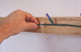 This is a lifestyle image showing the clear light clip being used on a piece of wood and holding a light string.