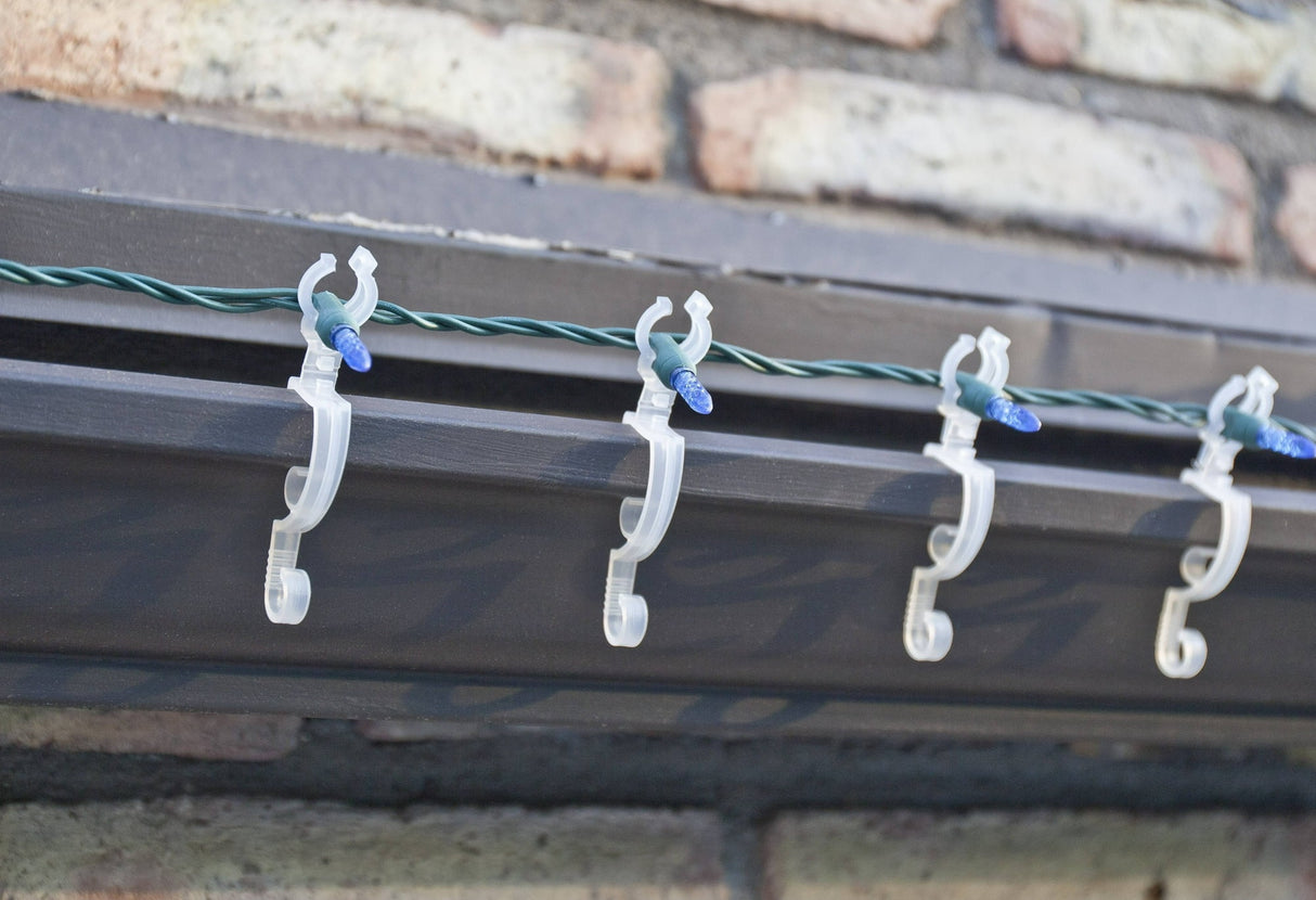 This is a lifestyle image showing the light clips holding a string of lights on the edge of a roof.
