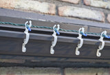 This is a lifestyle image showing the light clips holding a string of lights on the edge of a roof.