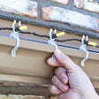 This is a lifestyle image showing these lights clips hanging from a roof and holding a light string.