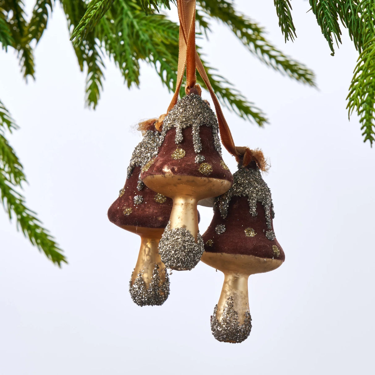 Ornament featuring three mushrooms covered in felt and glitter. Colors are Acorn Brown, Gold and Silver.