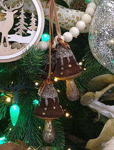 Ornament featuring three mushrooms covered in felt and glitter. Colors are Acorn Brown, Gold and Silver.