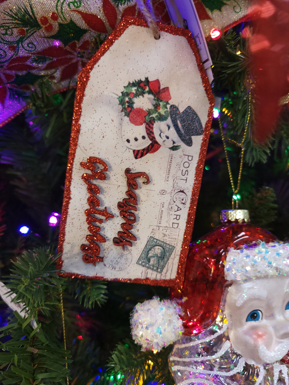 Gift tag ornaments designed to look like post cards. One ornament features a snowman and reads "Season's Greetings." One ornament features a deer and reads "Happy Holidays." One ornament features Santa Claus and reads "Merry Christmas."