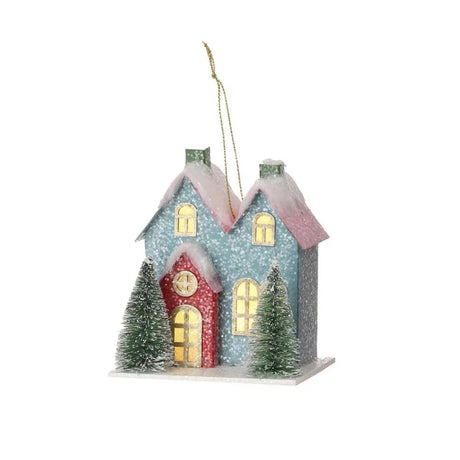 Christmas ornament shaped like a cute house with two trees in the front. One is blue with a red door and one is red with a pink door. LED lights are visible inside from the windows.