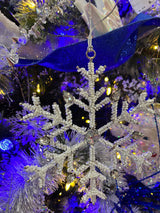 Ornament shaped like a snowflake and decorated with white beads and silver jewel accents.