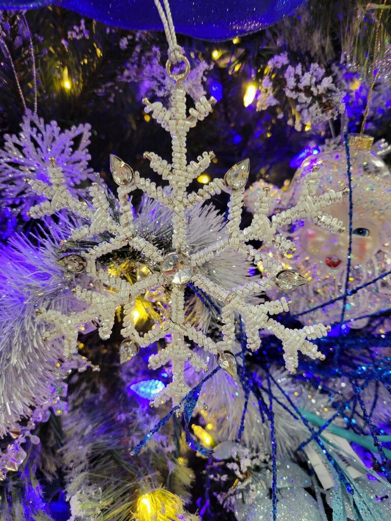 Ornament shaped like a snowflake and decorated with white beads and silver jewel accents.