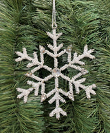 Ornament shaped like a snowflake and decorated with white beads and silver jewel accents.