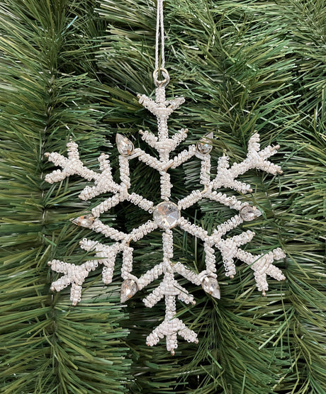 Ornament shaped like a snowflake and decorated with white beads and silver jewel accents.