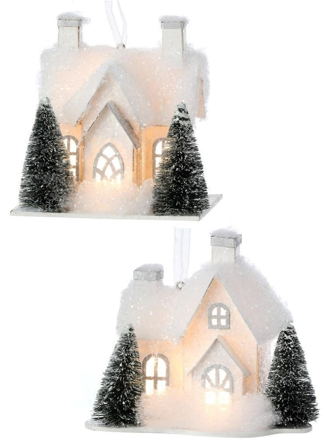 Ornament designed to look like a small house with three windows and two chimneys. Both homes are covered in white glitter and fluff and have two snow-covered trees in the front yard. There are two different options.