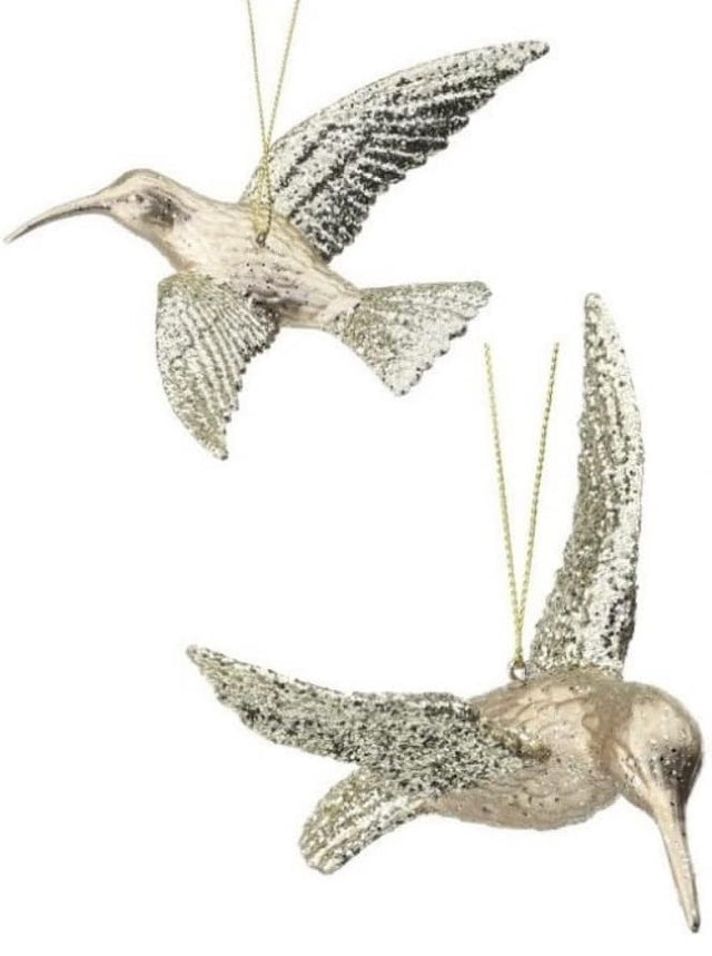 Ornament shaped like a hummingbird. The body is champagne colored and the wings are covered in gold glitter.