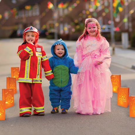 This is a lifestyle image showing these luminary bags in use. This picture shows three children walking along a pathway lined with them. One child is dressed like a firefighter. One child is dressed like a blue monster. The third child is dressed like a pink princess.