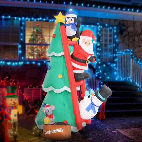 Christmas inflatable shaped like a penguin, Santa and a snowman climbing a red ladder leaning up against a Christmas tree. They're putting the finishing touches on the tree decorating. There's a little box at the bottom with a mouse holding an ornament. The box reads "DECK THE HALLS."