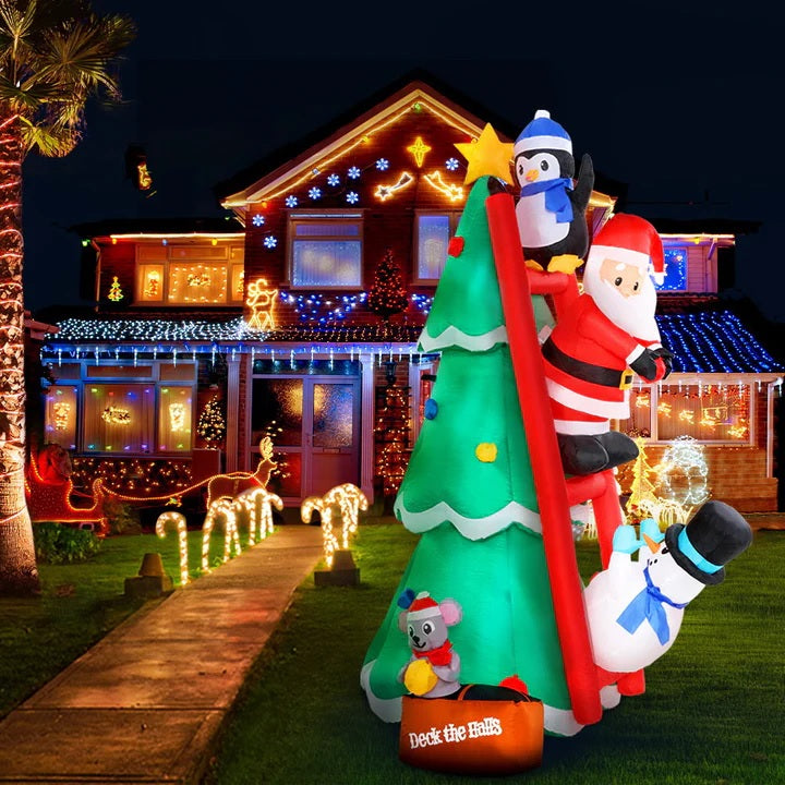 Christmas inflatable shaped like a penguin, Santa and a snowman climbing a red ladder leaning up against a Christmas tree. They're putting the finishing touches on the tree decorating. There's a little box at the bottom with a mouse holding an ornament. The box reads "DECK THE HALLS."