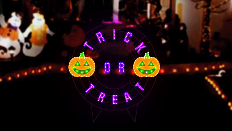 A black wire frame wreath with purple words that read "TRICK OR TREAT." There are two orange jack-o-lanterns with green eyes and mouths.