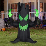 This image shows the Black Spooky Tree Inflatable in front of a house decorated for Halloween. The tree is black with a lime green mouth and green hands.