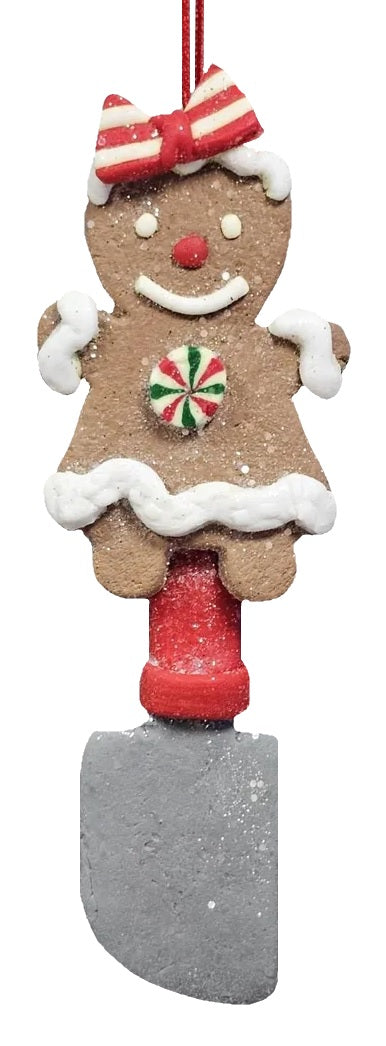 This image shows the gingerbread woman wearing a bow on her head, has frosting sleeves and a frosting hem on her dress. She also features a spatula.