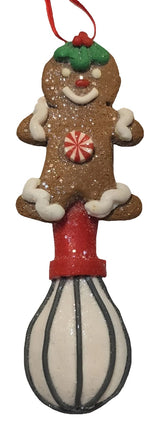 This image shows the gingerbread man wearing holly leaves and berries on his head and features frosting sleeves and frosting pant cuffs. It also features a whisk.