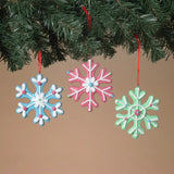 This is a lifestyle image showing the three different ornaments hanging from a tree branch.