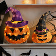 This is a lifestyle image showing these two decorative pumpkins on a mantel in a room decorated for Halloween.