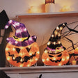 Set of 2 lighted jack-o-lantern decorations. One is wearing a purple witch hat with bats on it. The other is wearing a black witch hat.